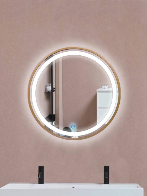 Espejo en forma circular con perímetro interior iluminado y el exterior en dorado colocado arriba de un lavamanos y refleja accesorios de baño