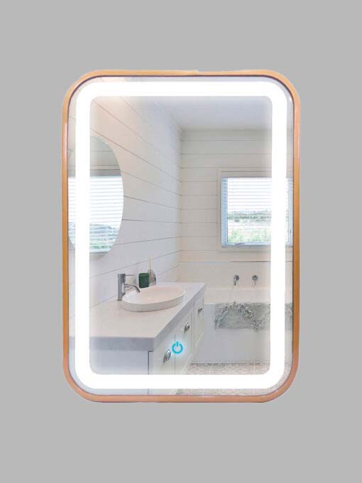 Espejo rectangular con contorno interior iluminado y el exterior en dorado, refleja la imagen de un baño con lavamanos, ventana y otro espejo