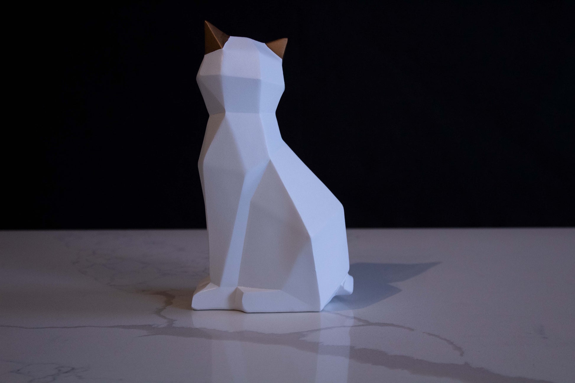 Figura de ornato en forma de gato blanco sentado con orejas doradas vista de costado