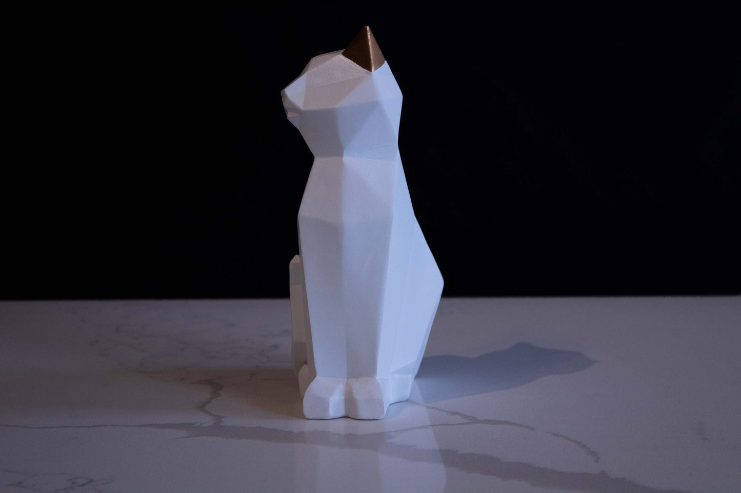 Figura de ornato en forma de gato blanco sentado con orejas doradas vista de perfil contorno con líneas marcadas