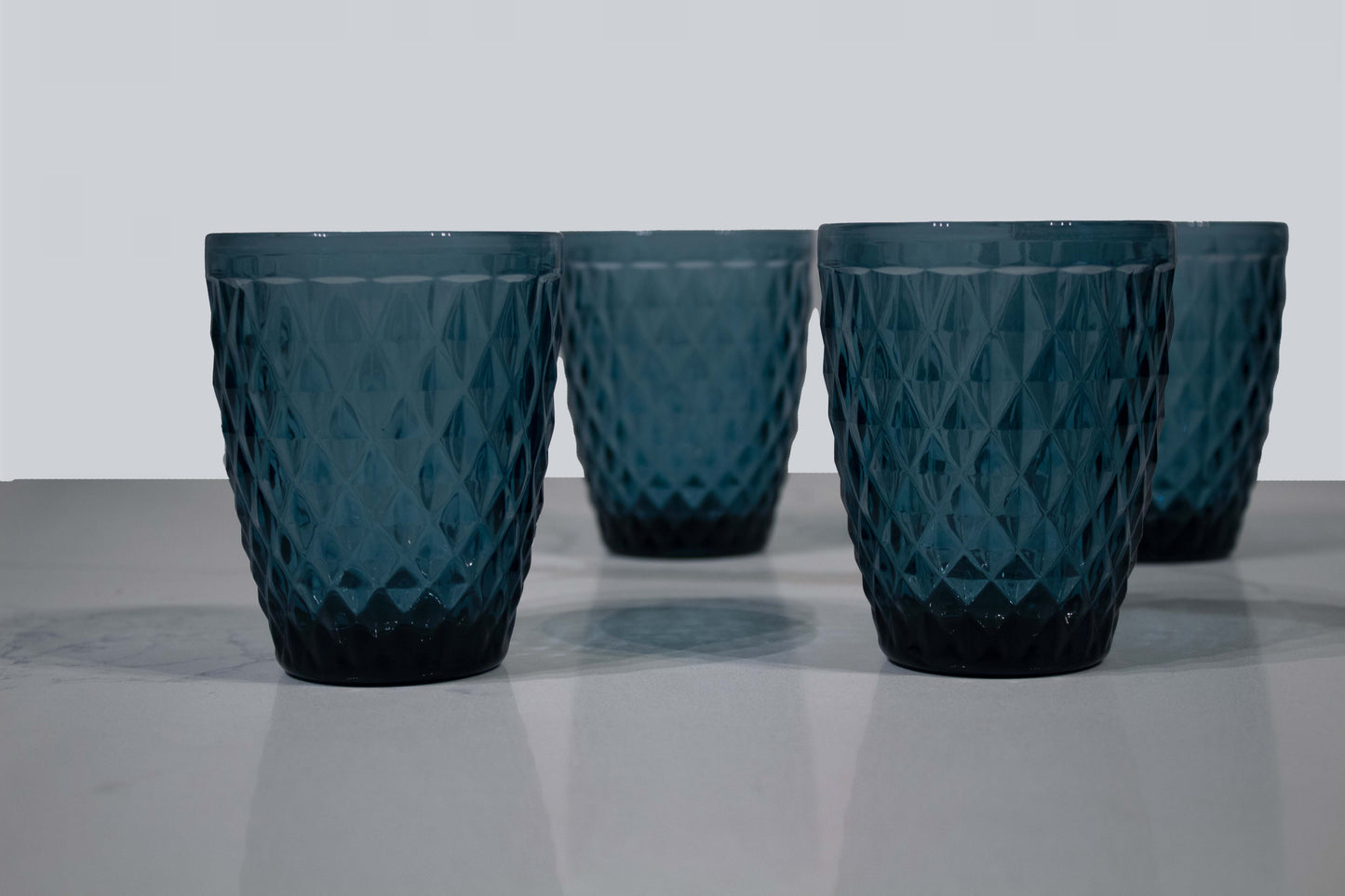 Cuatro vasos de cristal azul con diseño en forma de diamante