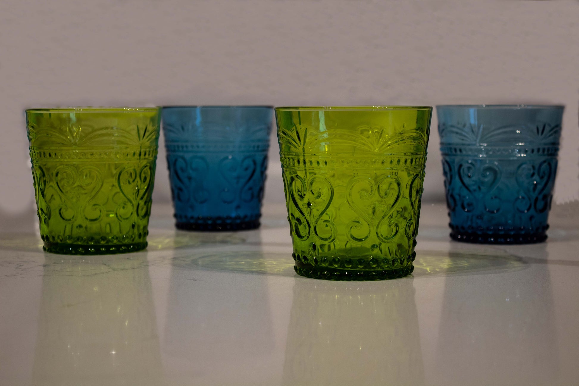 Cuatro vasos de cristal, dos verdes y dos azules con diseño de grecas y estilo de vidrio soplado